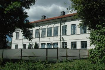 vit byggnad med många fönster inramad av flera träd