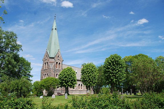 en stenkyrka med en trädallé framför.
