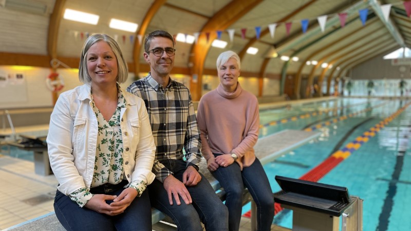 Jenny, Dan och Anna sitter på trampolinen framför simbassängen i Gislebadet.