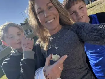 Foto på en pedagog och två elever, de har kryss på sina händer.