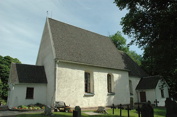 en gammal stenkyrka med gravstenar framför.