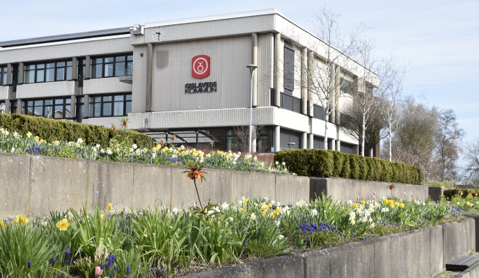 Kommunhuset med vårblommor i förgrunden.