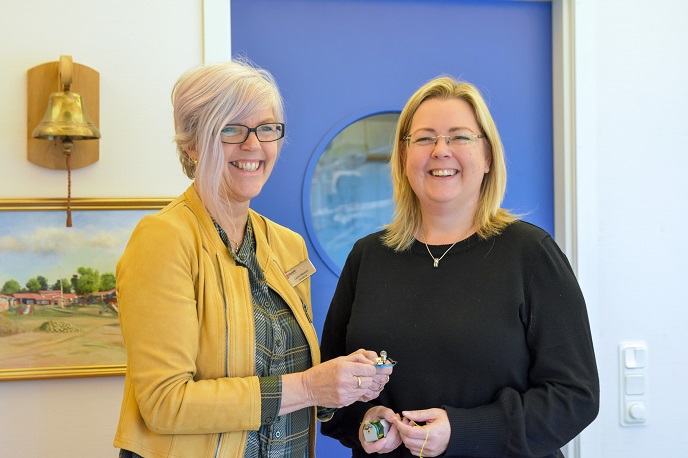 Två glada kvinnor framför en blå dörr