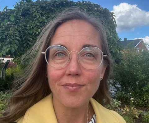 Foto på en kvinna med glasögon, långt brunt hår.