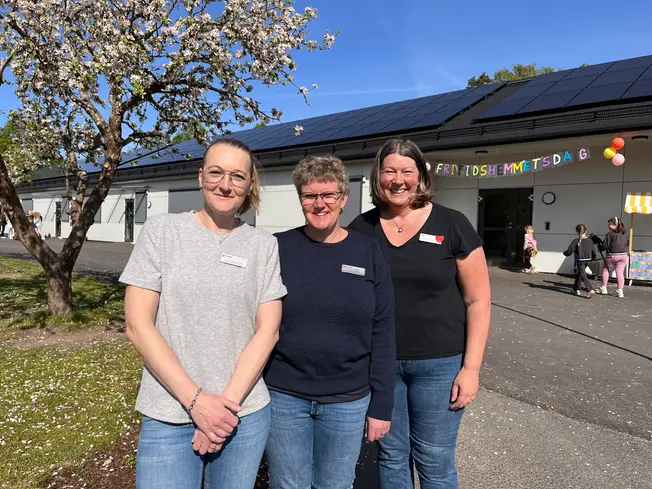 Foto på tre pedagoger framför skolan.