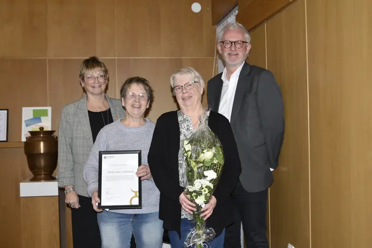 Tre kvinnor och en man tittar leende in i kameran. Kvinnorna längst fram i bild håller i ett diplom och en blombukett.