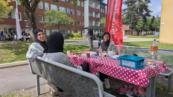 Tre kvinnor sitter vid en parkbänk och har förberett ansiktsmålning för alla barn.