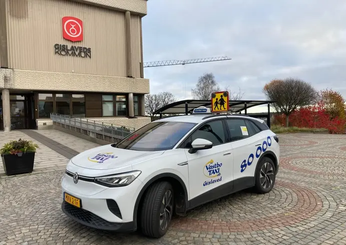 En vit bil som står framför kommunhuset.