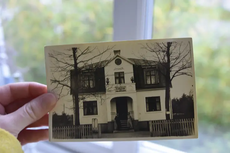 En hand som håller i ett svartvitt foto av ett hus.