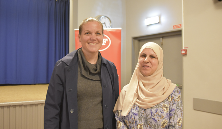 Två kvinnor står leende bredvid varandra.