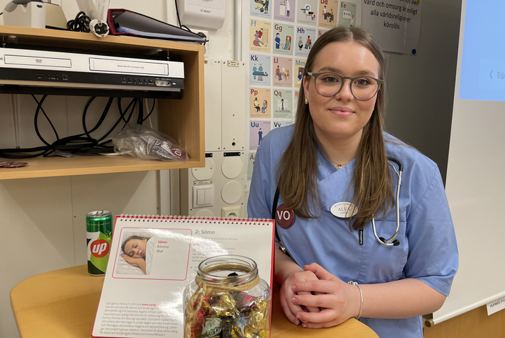 En ung kvinna i blå arbetskläder ler mot kameran.