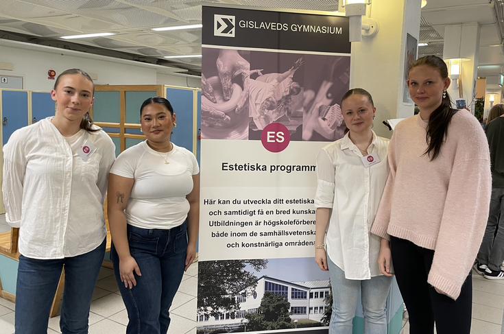 Fyra unga kvinnor framför en rollup med information om Estetiska programmet.