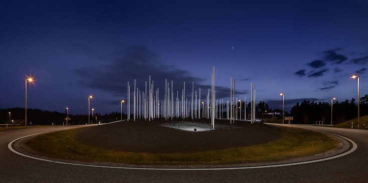 en rondell med ett konstverk i form av höga pinnar