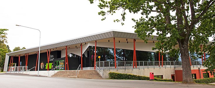 ett hus med stora glasfönster och röda pelare på utsidan