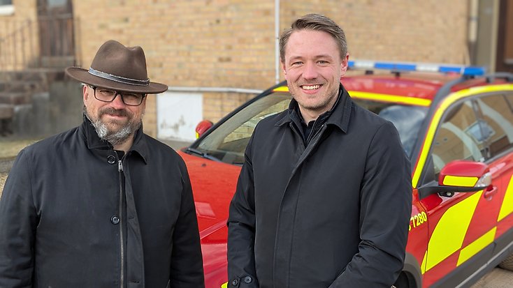 Niclas Palmgren som är ordförande i räddningsnämnden Gislaved-Gnosjö står bredvid Alexander Josefsson som är platschef vid brandstationen i Hestra. Bakom dem ser man en rödgul bil som hör hemma hos räddningstjänsten.