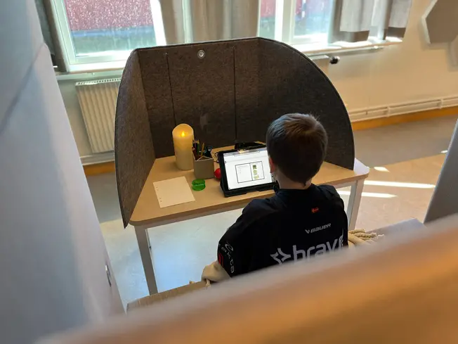 Foto på en elev, taget bakifrån. Man ser hens rygg och hen sitter och målar.