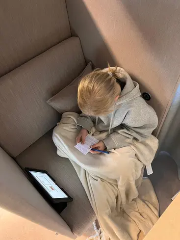 Foto på en elev taget ovanifrån, hen sitter i en fotölj med en filt.