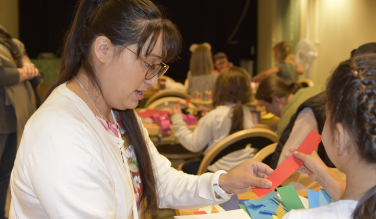 Kristina, bibliotekarie, visar hur man gör en girlang av pappersremsor och tejp.