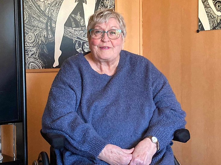 En äldre kvinna, Yvonne Boqvist, sitter i en rullstol och tittar in i kameran.