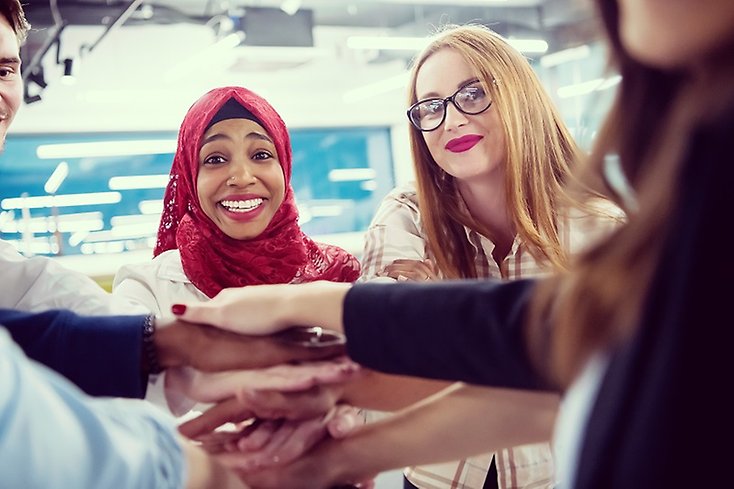 Unga människor i grupp för samman händerna