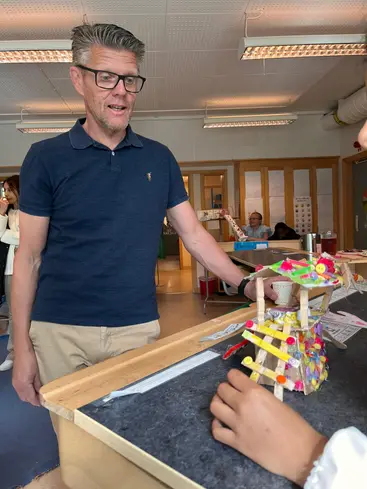 Foto på en man som beundrar elevernas uppfinningar.