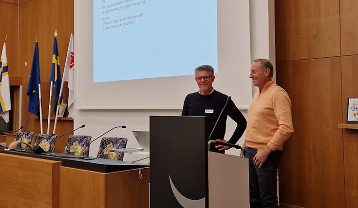 Två män står vid ett podie.