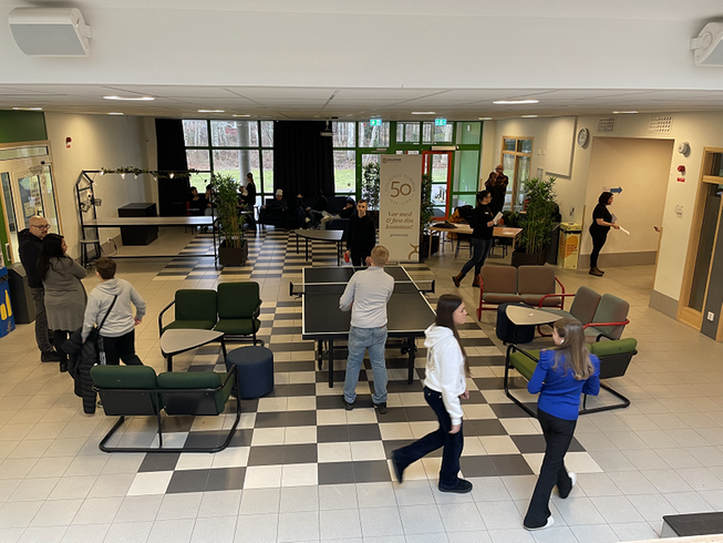 Nordinskolans ljushall där elever umgås och bland annat spelar pingis. I bakgrunden pratar medarbetare från kommunen med elever.