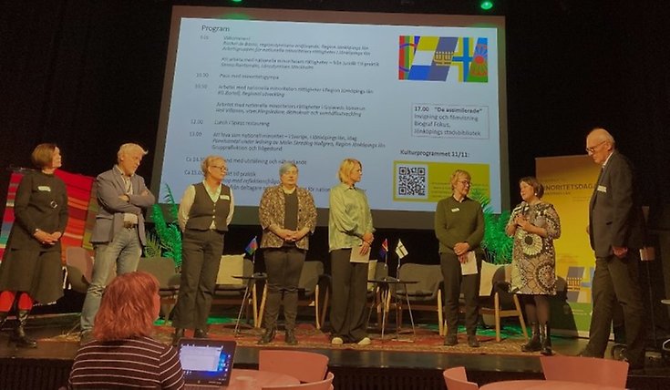 8 personer står bredvid
varandra på en scen.