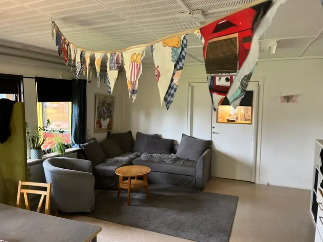 Foto på ett rum med en stor gosig soffa i, det hänger vimplar i taket.